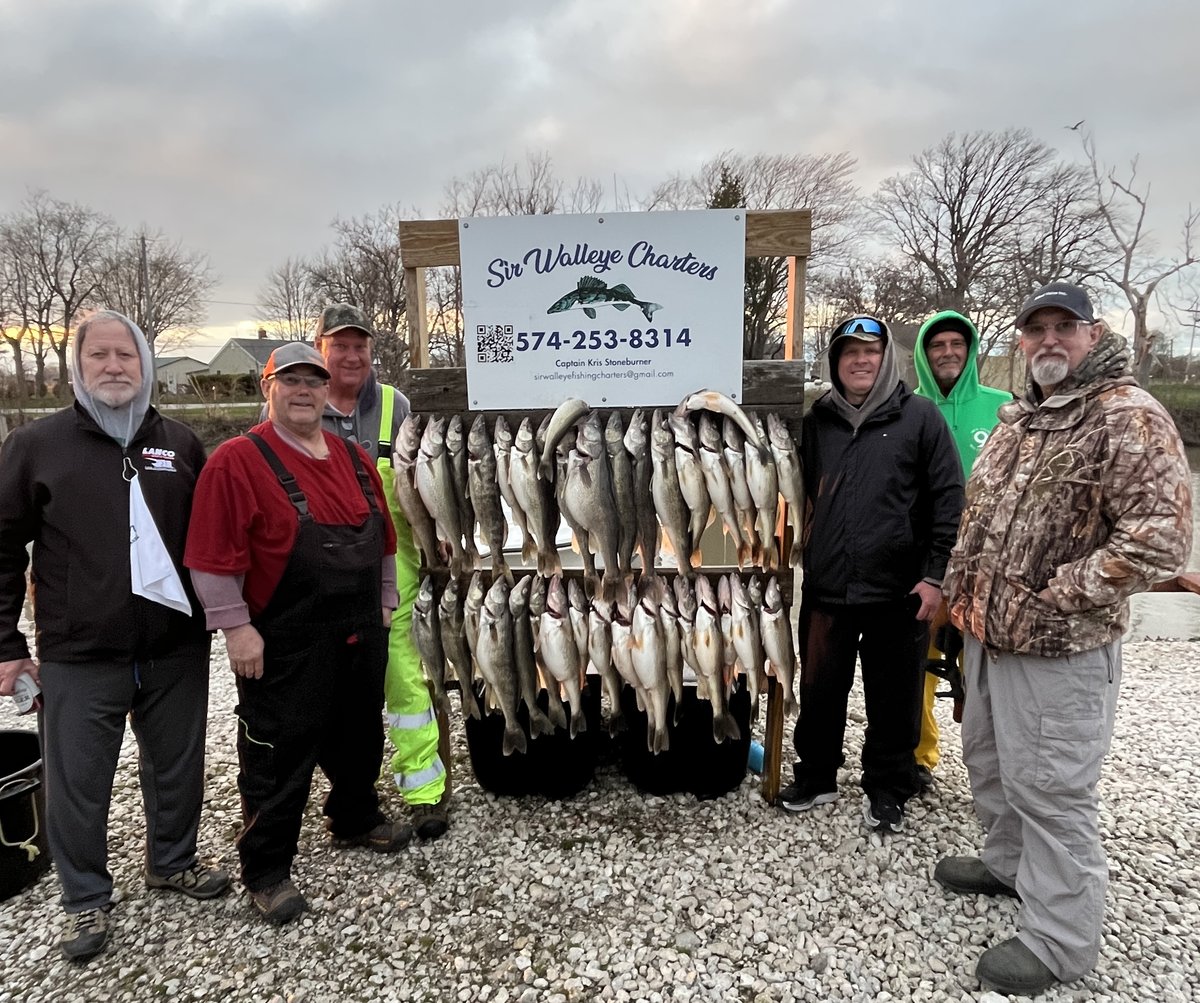 A group of anglers with their Lake Erie walleye limit beside the Sir Walleye Charters sign