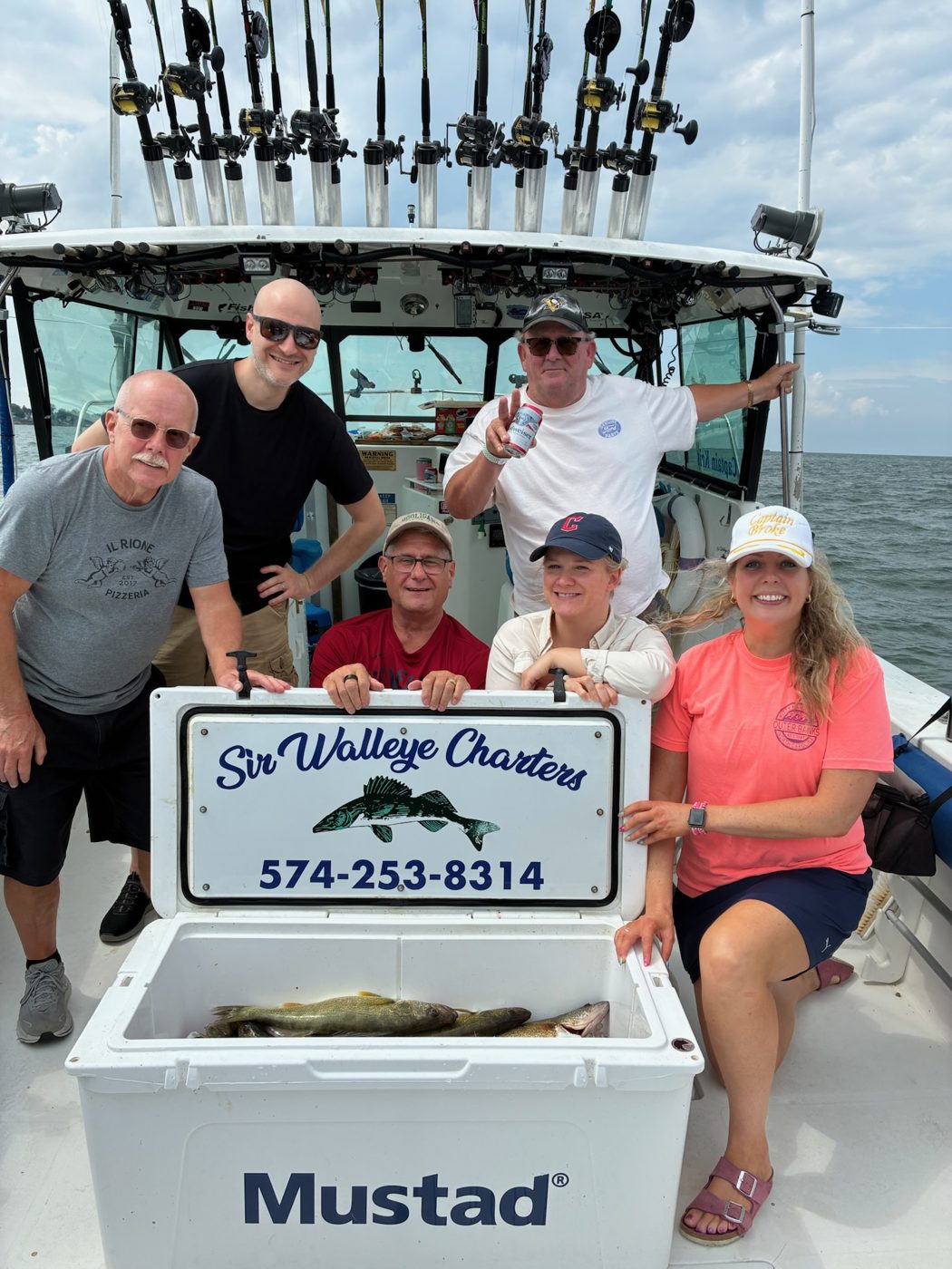 Sir Walleye Charters group behind the branded boat sign with a cooler of Central Basin Lake Erie walleye out of Lorain, Ohio