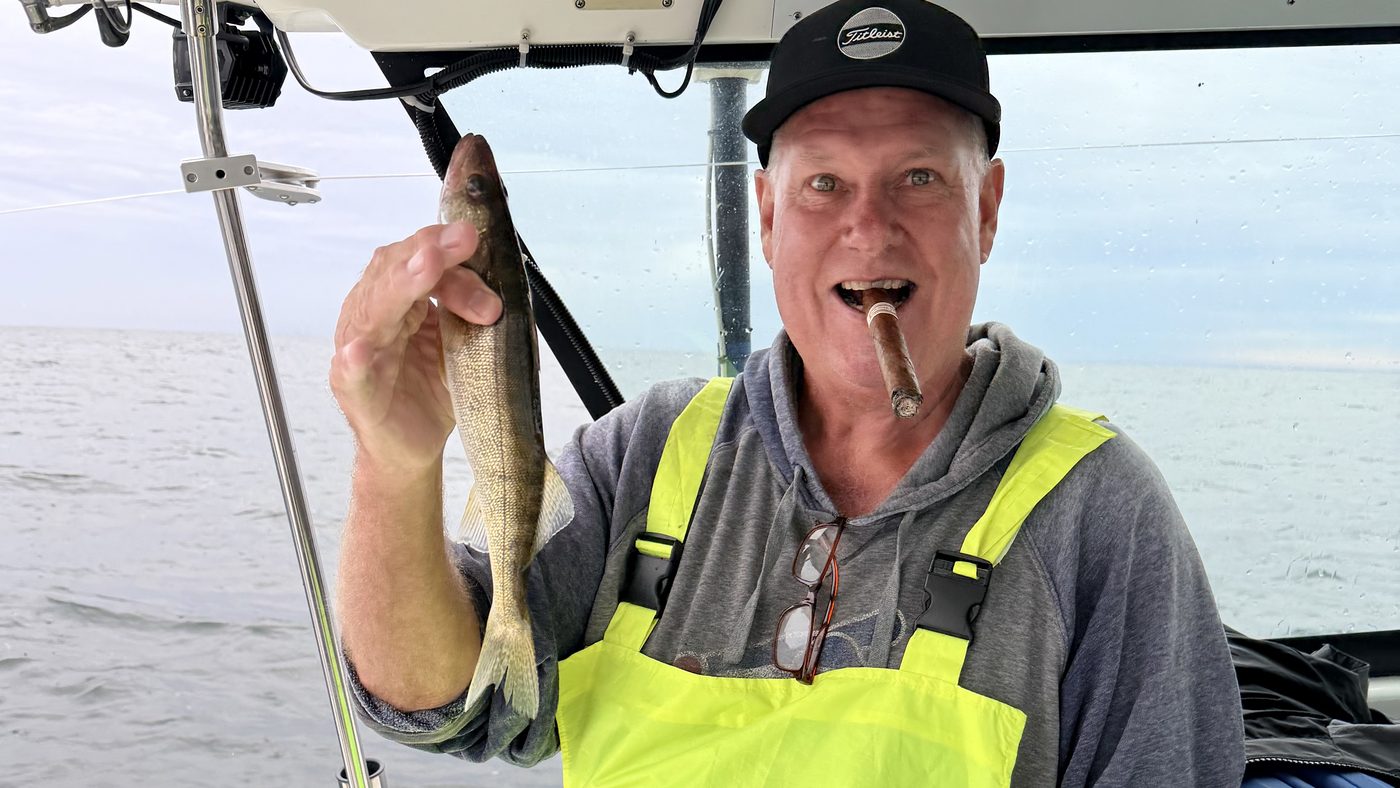 Angler in bibs holding a Lake Erie walleye aboard Sir Walleye Charters on a Central Basin trip out of Lorain, Ohio